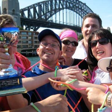 Sydney Amazing Race winners hold the Trophy beneath Sydney Harbour Bridge